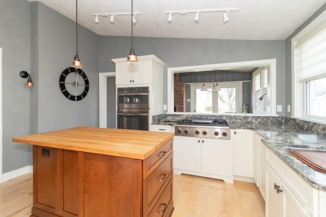 kitchen with butcher block counters, white cabinets, appliances with stainless steel finishes, and track lighting