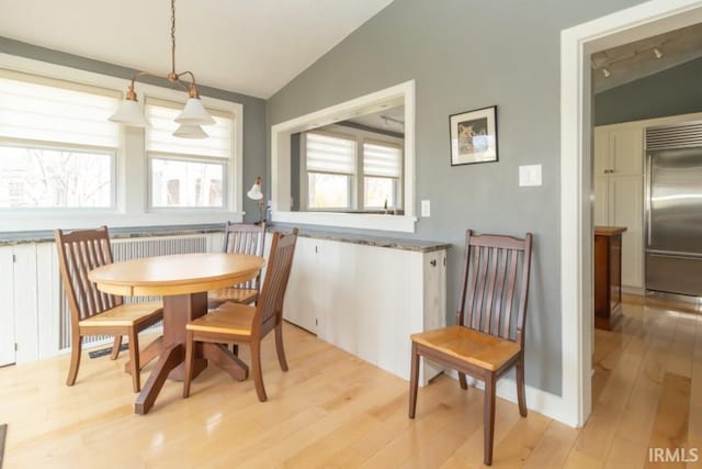 dining area featuring lofted ceiling, plenty of natural light, and light hardwood / wood-style flooring