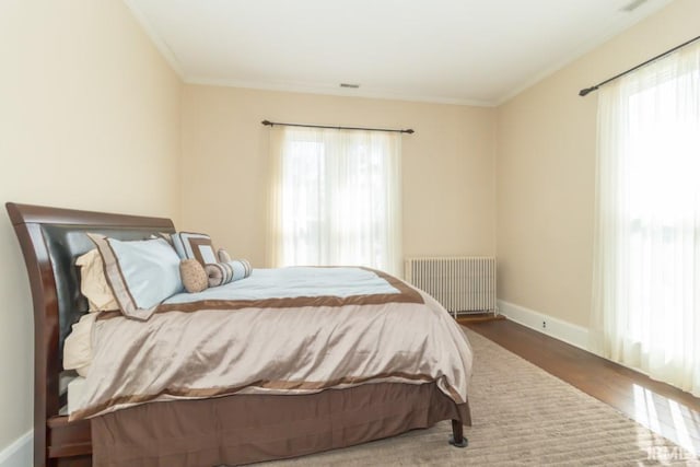 bedroom with radiator heating unit, ornamental molding, dark hardwood / wood-style floors, and multiple windows