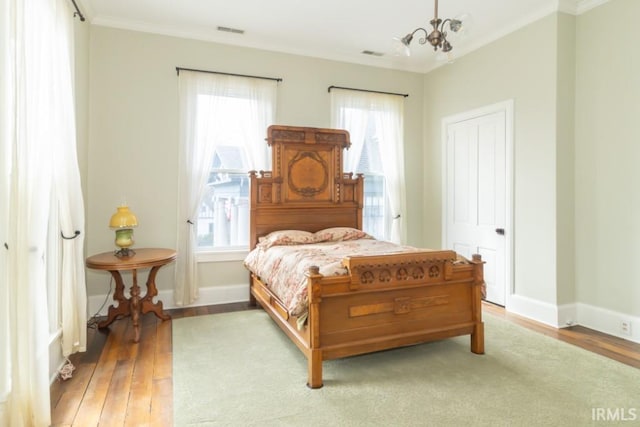 bedroom featuring multiple windows, light hardwood / wood-style flooring, and ornamental molding