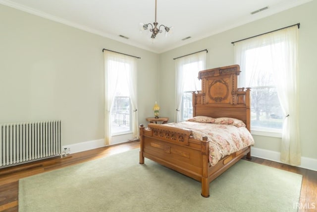 bedroom featuring radiator heating unit, a chandelier, and multiple windows