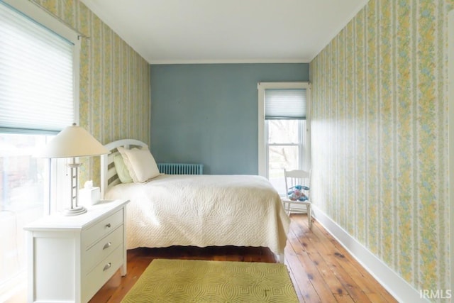 bedroom with multiple windows, radiator, and light wood-type flooring