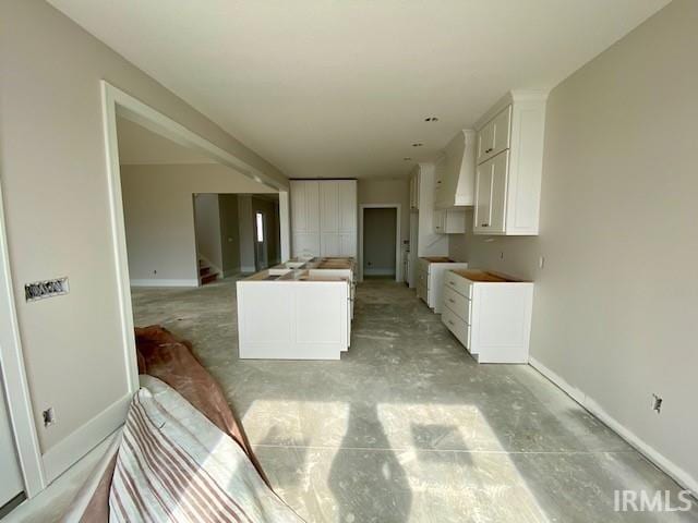 kitchen with white cabinetry and custom range hood