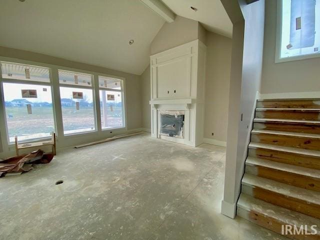 unfurnished living room with lofted ceiling with beams and plenty of natural light