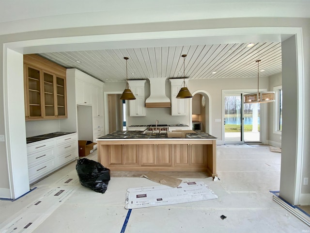 kitchen featuring hanging light fixtures, a kitchen island, white cabinetry, custom exhaust hood, and sink