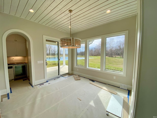 unfurnished dining area with beverage cooler and a water view