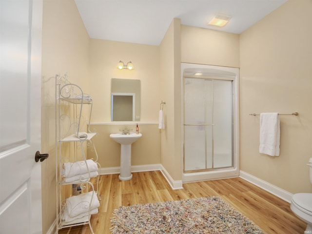 bathroom featuring hardwood / wood-style flooring, a shower with door, sink, and toilet