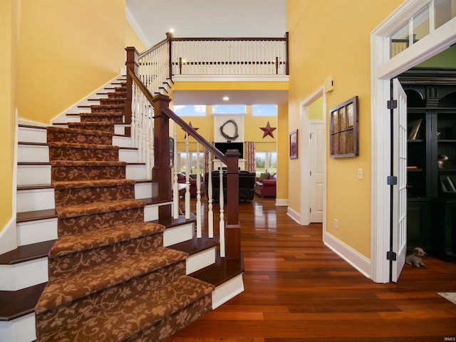 staircase with dark hardwood / wood-style floors and a high ceiling