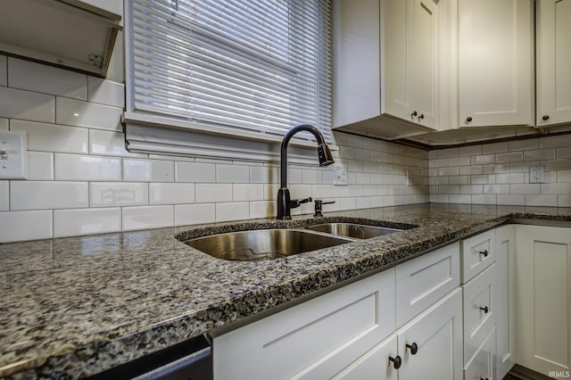 kitchen featuring dark stone countertops, white cabinets, and backsplash