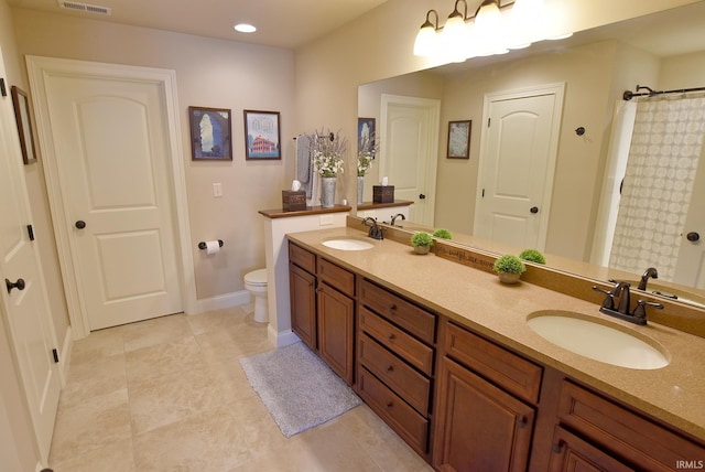 bathroom with dual vanity, tile flooring, and toilet