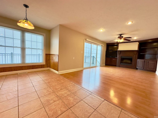 unfurnished living room featuring light tile floors and ceiling fan