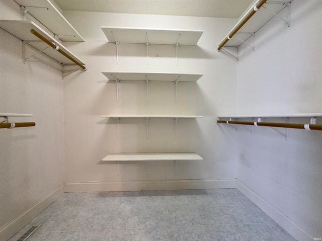 walk in closet with light tile floors