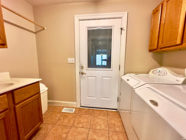 clothes washing area with light tile flooring, cabinets, and washer and dryer