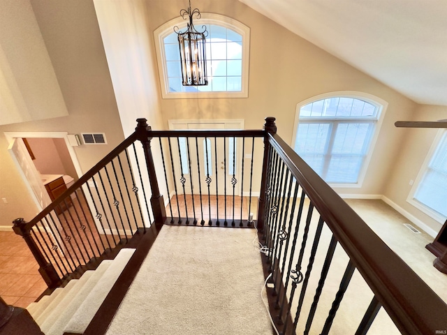 stairway featuring light colored carpet, high vaulted ceiling, and a chandelier