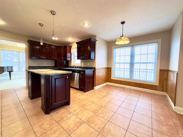 kitchen featuring pendant lighting, light stone counters, a kitchen island, dishwasher, and light tile flooring