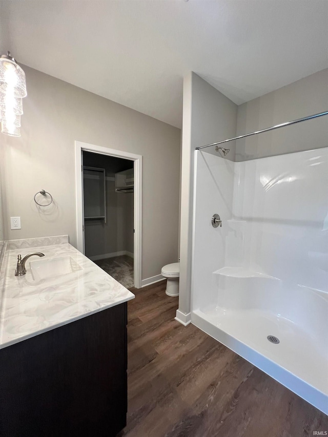 bathroom featuring an AC wall unit, wood-type flooring, vanity, toilet, and walk in shower