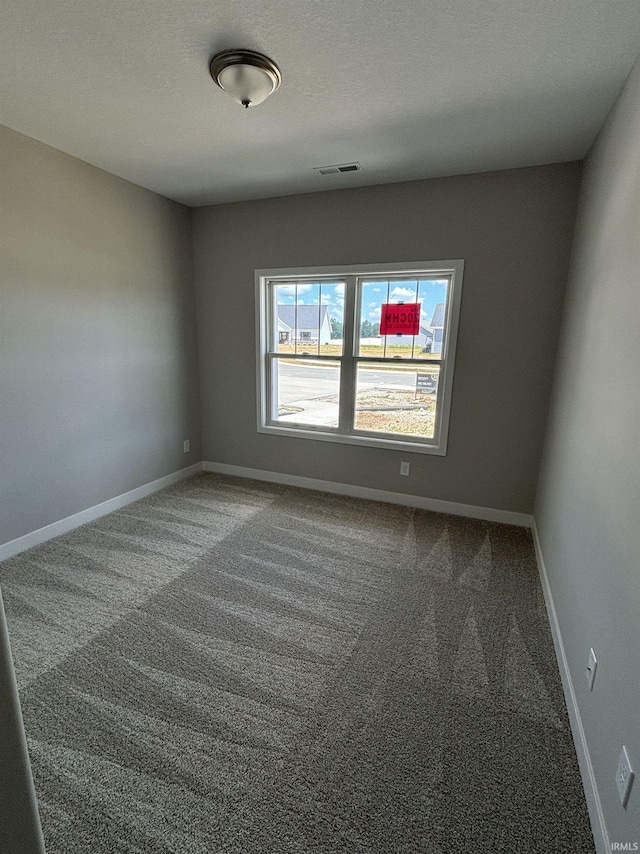 empty room with a textured ceiling and carpet floors