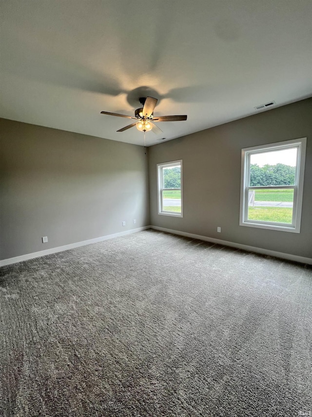 empty room featuring visible vents, baseboards, carpet, and a ceiling fan