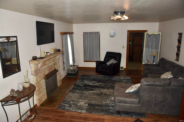 living room featuring a stone fireplace and dark hardwood / wood-style flooring