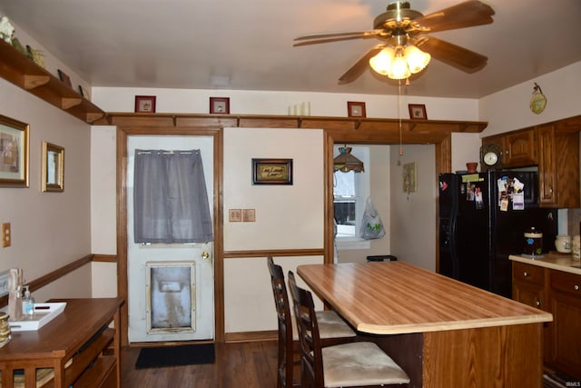 kitchen featuring black fridge, a center island, ceiling fan, and dark wood-type flooring