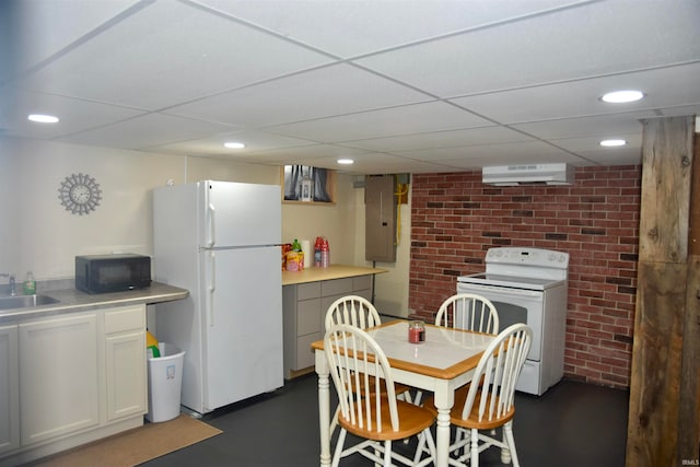 dining area with brick wall, a wall mounted AC, a drop ceiling, and sink