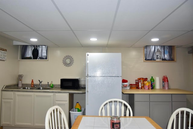 kitchen featuring white fridge, sink, a drop ceiling, and gray cabinets