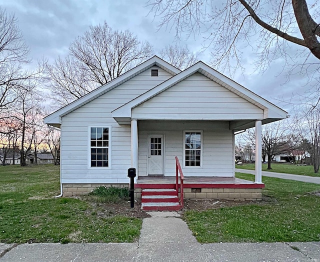 bungalow-style home featuring covered porch and a front lawn