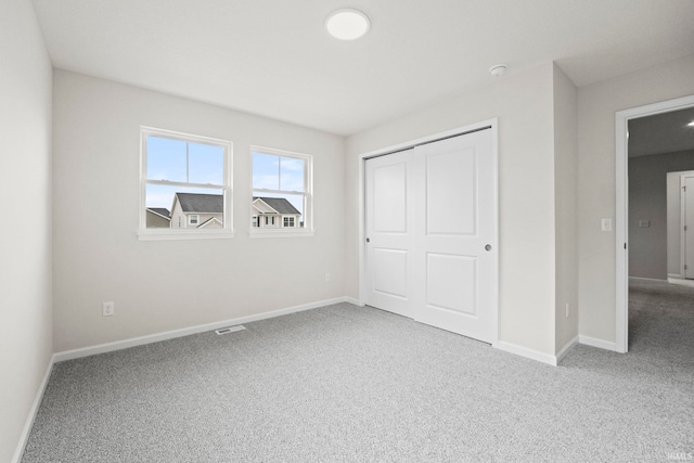 unfurnished bedroom with light carpet and a closet