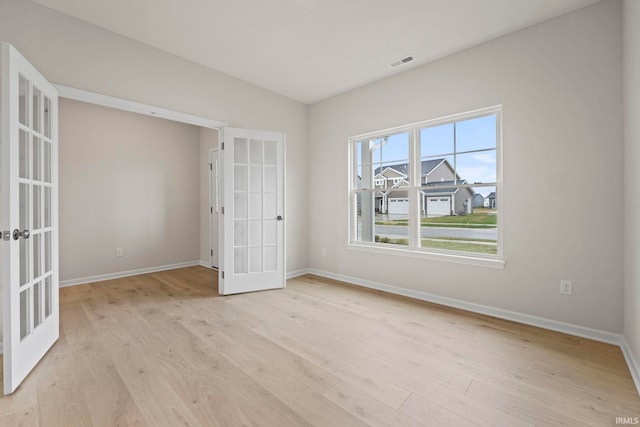 spare room with light hardwood / wood-style flooring, a healthy amount of sunlight, and french doors