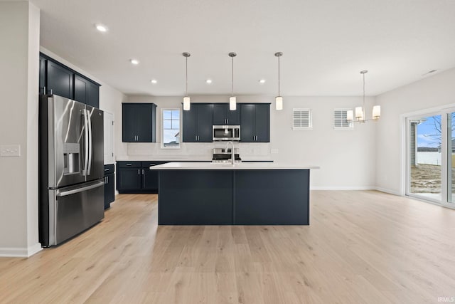 kitchen with decorative light fixtures, light wood-type flooring, and stainless steel appliances