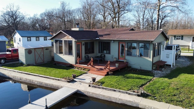 view of front facade with a deck, a storage shed, and a front yard