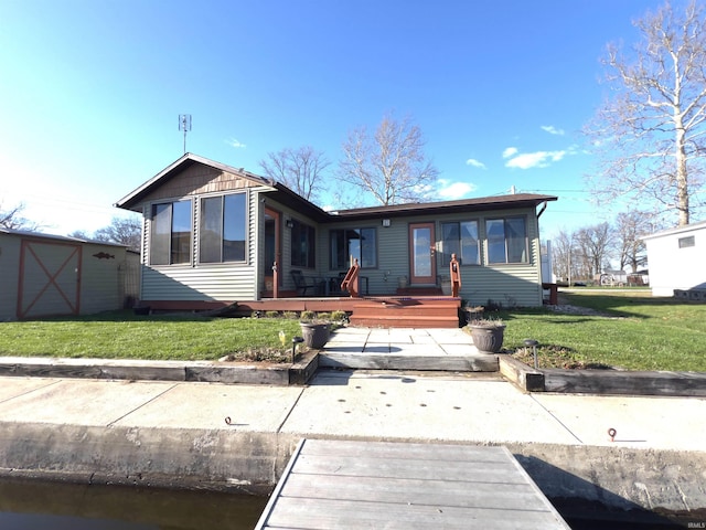 back of property with a wooden deck, a yard, and a storage unit