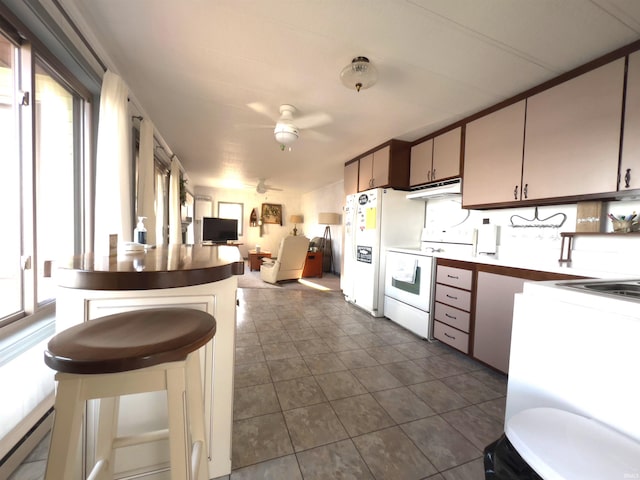 kitchen with dark tile floors, a breakfast bar, tasteful backsplash, electric range, and ceiling fan