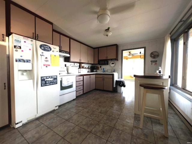 kitchen with plenty of natural light, dark tile flooring, and white appliances