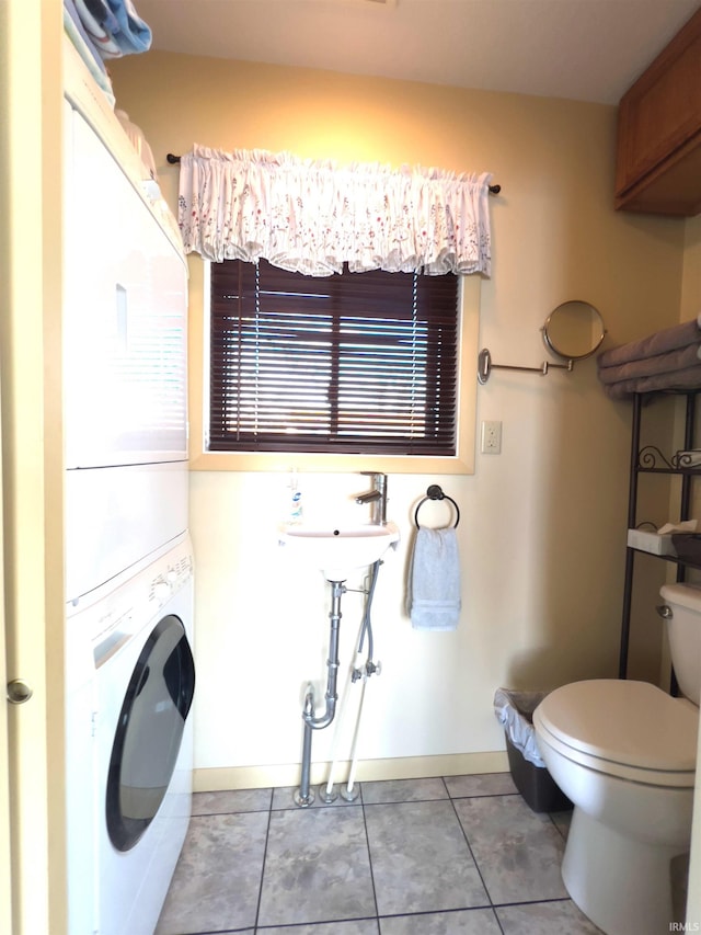 interior space with tile flooring, stacked washer and clothes dryer, and toilet