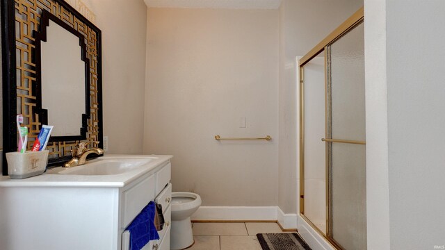 bathroom with tile flooring, toilet, vanity, and a shower with door