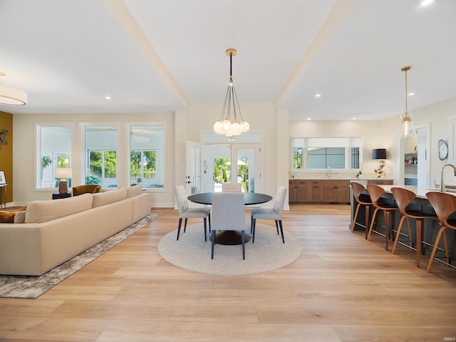 dining room featuring french doors, an inviting chandelier, sink, and light wood-type flooring