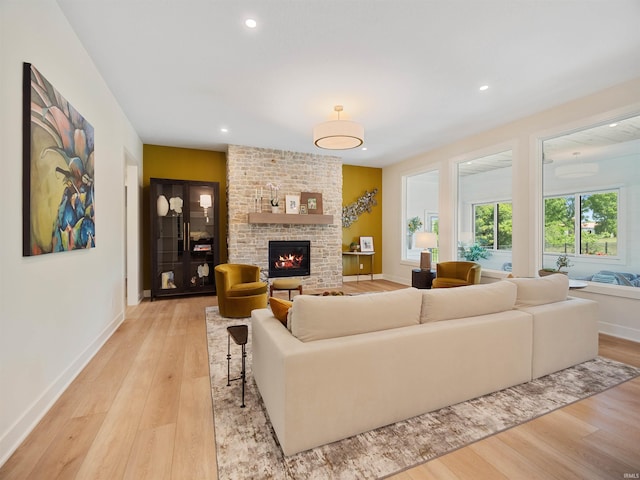 living room featuring brick wall, light hardwood / wood-style floors, and a brick fireplace