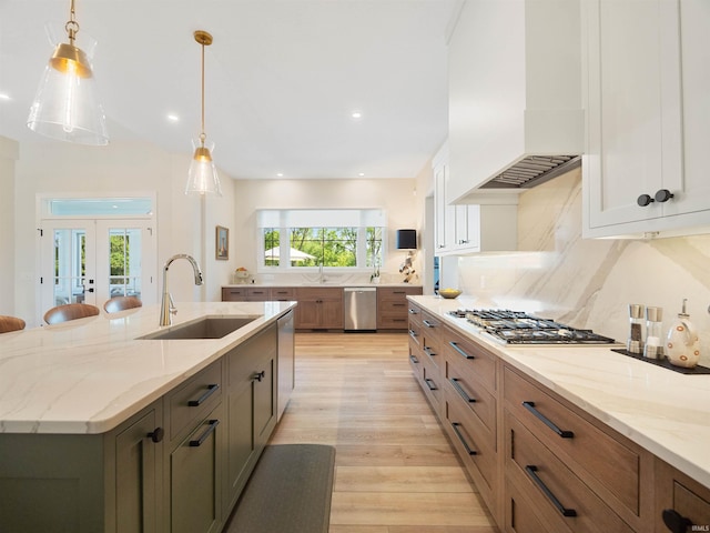 kitchen with light stone countertops, french doors, white cabinetry, sink, and light hardwood / wood-style floors