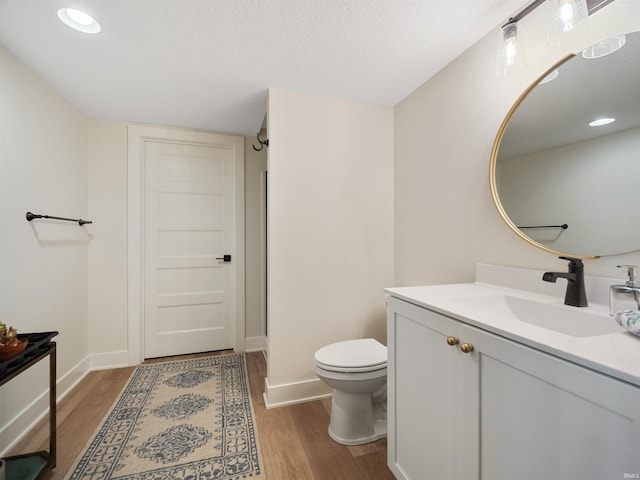 bathroom with hardwood / wood-style flooring, toilet, a textured ceiling, and large vanity