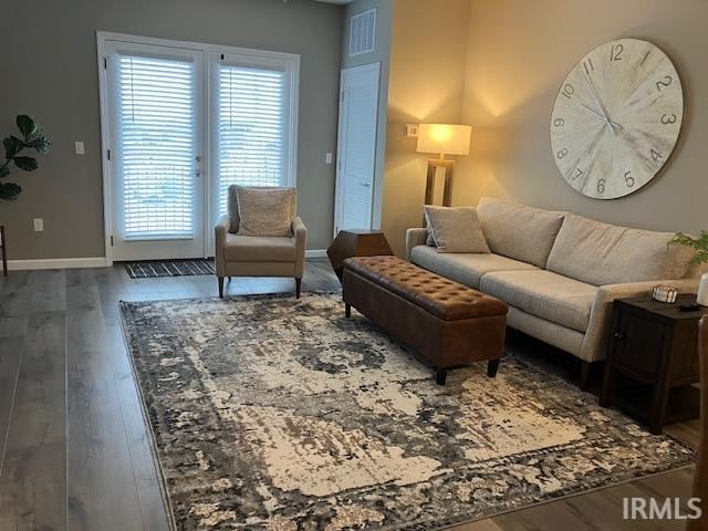 living room with a wealth of natural light and dark wood-type flooring