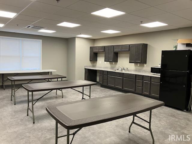 kitchen featuring black fridge, a paneled ceiling, and sink