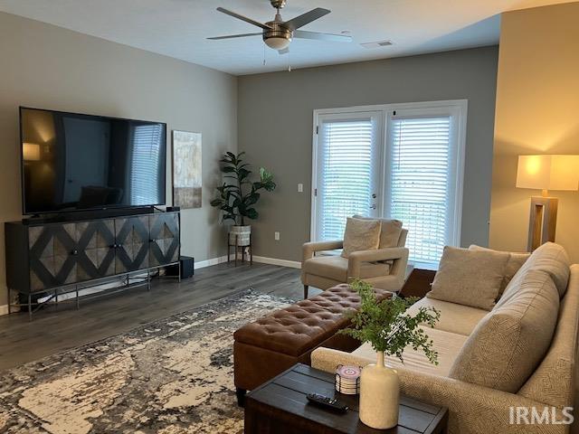 living room featuring ceiling fan and dark wood-type flooring