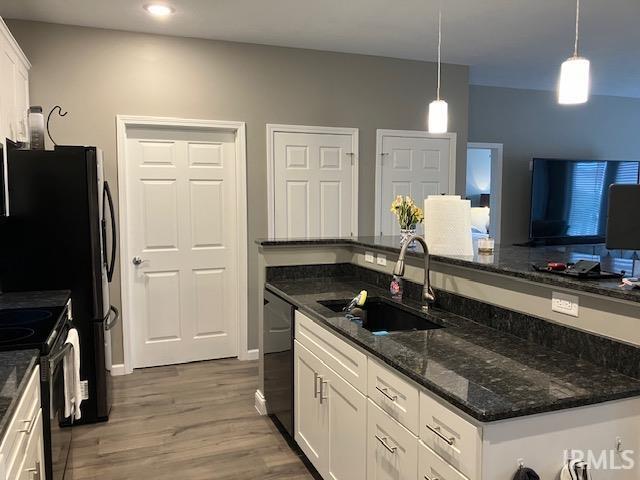 kitchen featuring decorative light fixtures, dark stone counters, white cabinets, dark hardwood / wood-style floors, and sink