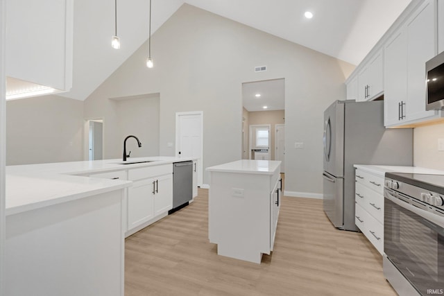 kitchen featuring appliances with stainless steel finishes, high vaulted ceiling, a kitchen island, and pendant lighting