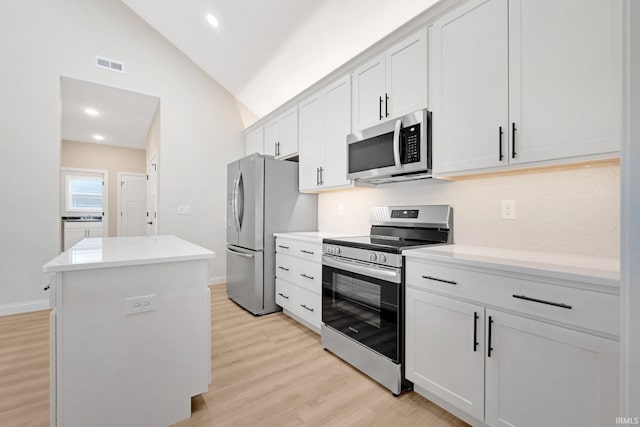 kitchen with white cabinetry, light hardwood / wood-style flooring, stainless steel appliances, and vaulted ceiling