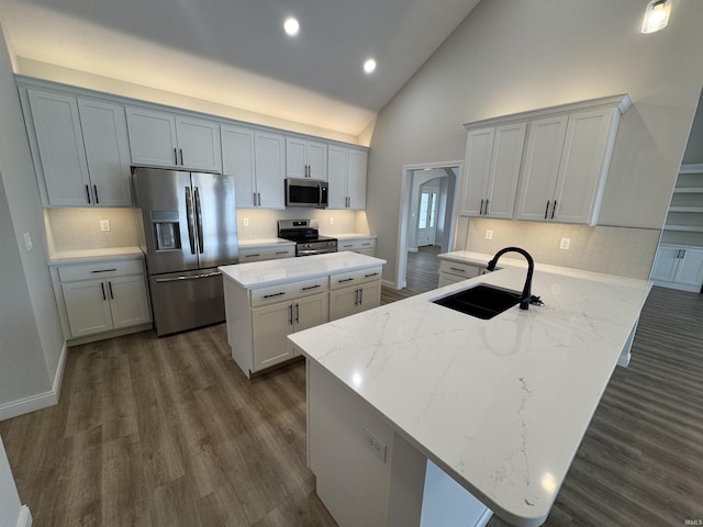 kitchen with kitchen peninsula, stainless steel appliances, dark wood-type flooring, sink, and high vaulted ceiling