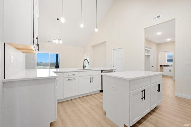 kitchen with pendant lighting, a center island, high vaulted ceiling, sink, and white cabinetry