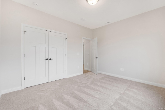 unfurnished bedroom featuring light carpet and a closet