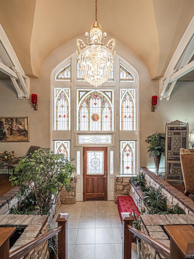 tiled entryway with a notable chandelier and a high ceiling